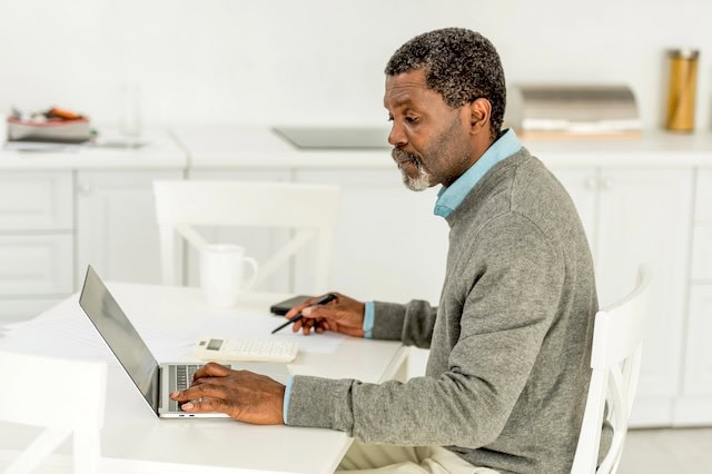 Our Guide to the New Senior Tax Deduction 7 senior man looking at laptop and calculator with pen and paper 640