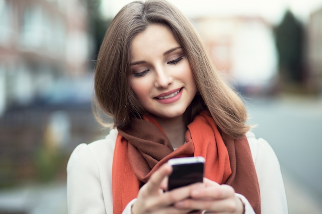 Woman texting. Closeup young happy smiling cheerful beautiful woman girl looking at mobile cell phone