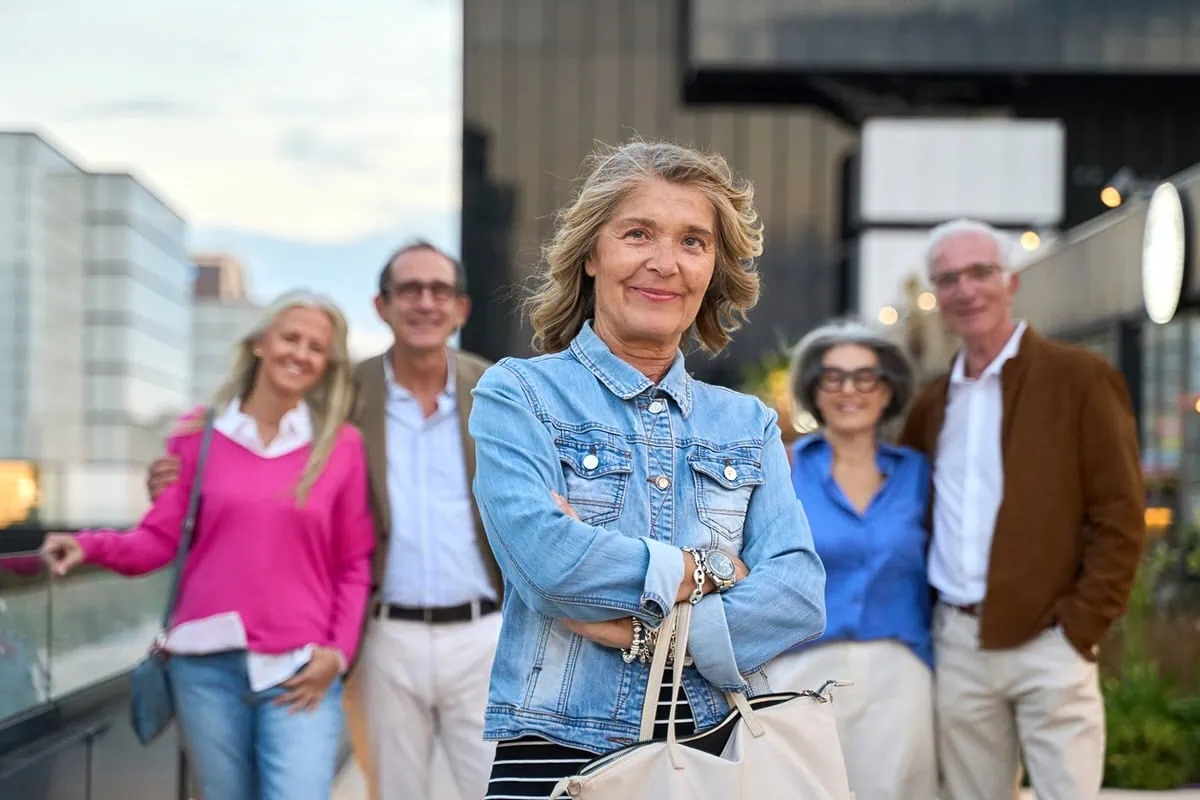 What Is FIRE? A Beginner's Guide to the Early Retirement Movement 16 A senior woman crosses her arms confidently while standing in front of other senior couples.
