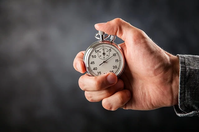 a man holds a stopwatch against a black background.