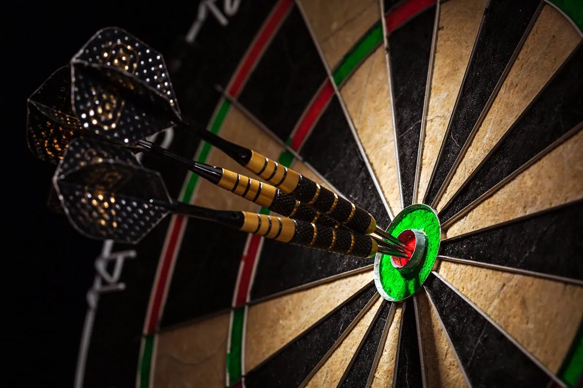 Beginner's Guide to Fidelity Target-Date Funds 2 a light shines on three darts sitting in the bullseye of a dartboard.