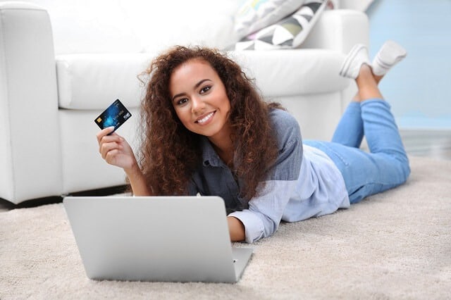 teenage girl with card at computer smiling