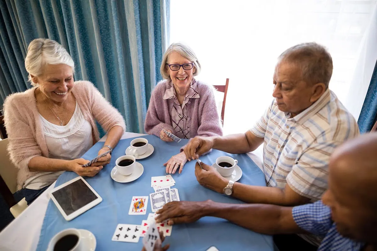 The Best Dividend Stocks: 10 Pro-Grade Income Picks for 2026 9 seniors play cards in a senior housing facility.