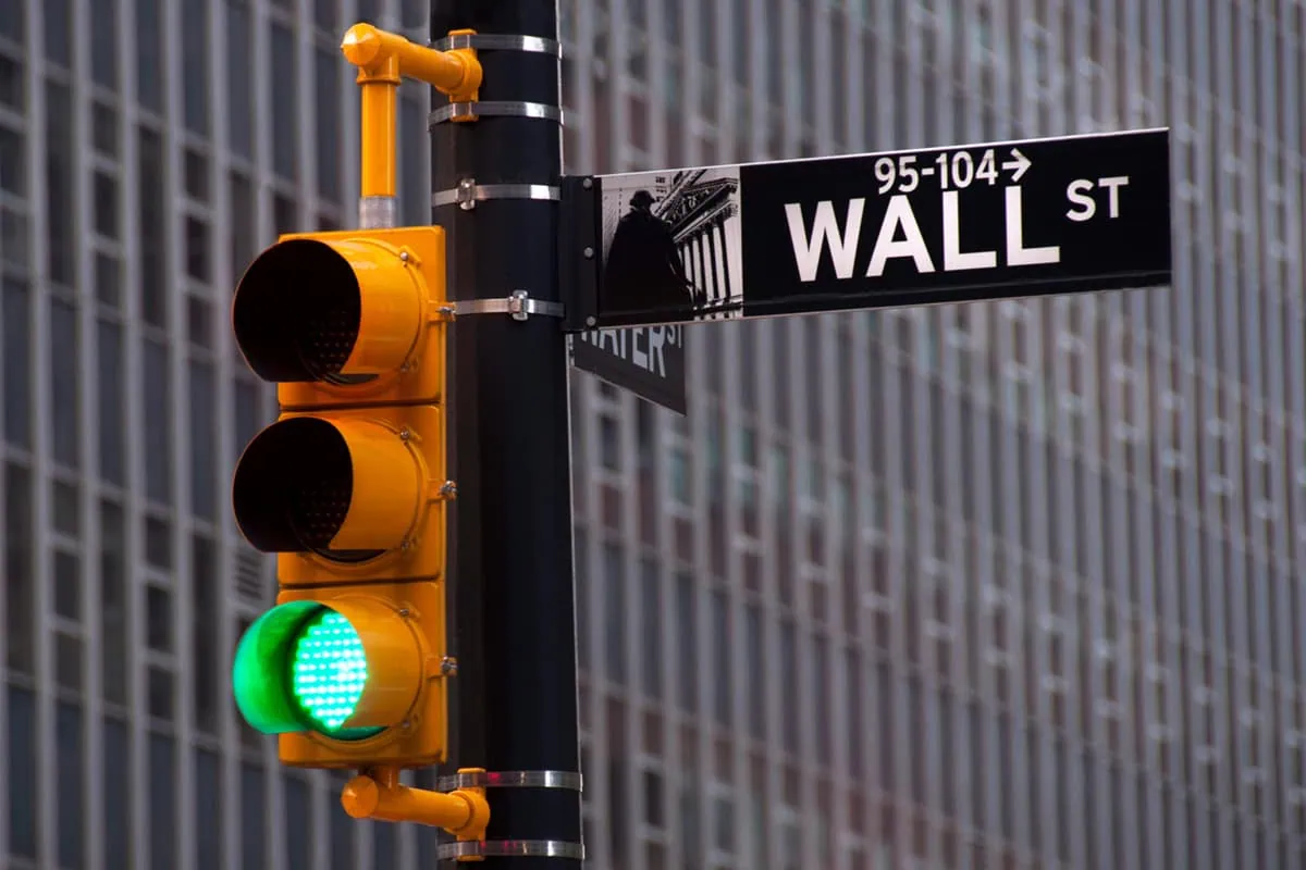 The 16 Best ETFs to Buy for a Prosperous 2026 11 a wall street street sign in the foreground and a traffic signal lit green in the background.