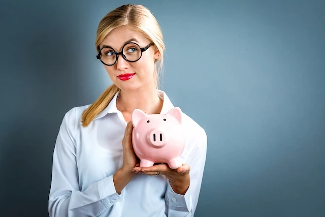 woman with glasses holding piggy bank