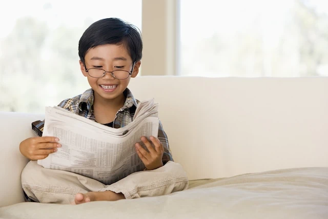 young boy on couch reading about stocks medium