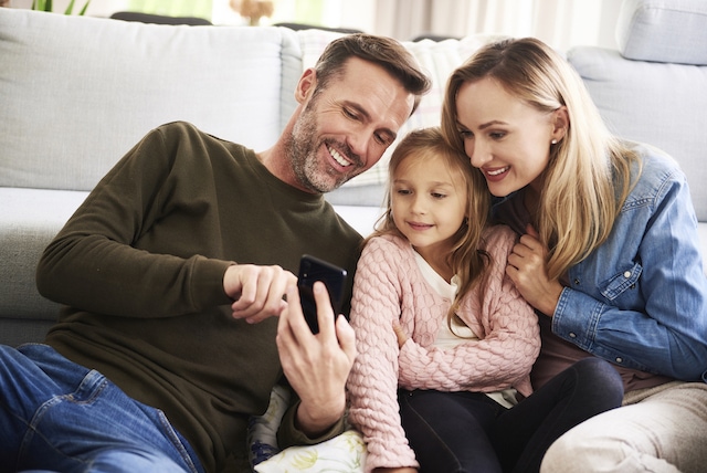 Parents and their daughter looking at mobile phone