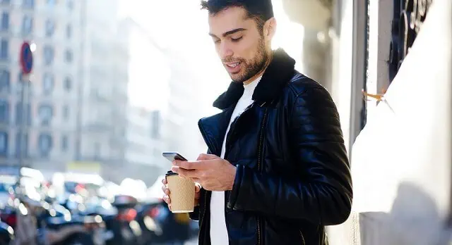 young man with coffee looking at phone