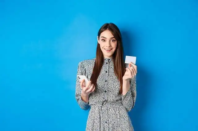 young woman holding credit card happy