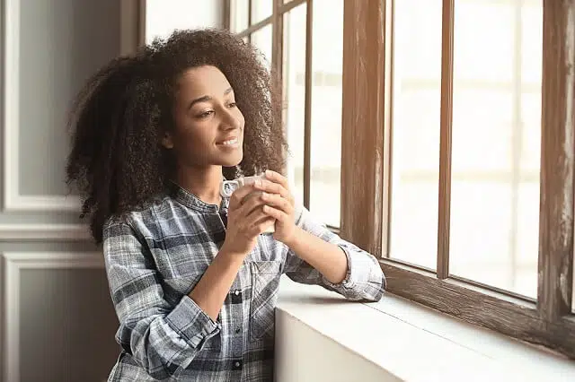 young woman looking out window happy