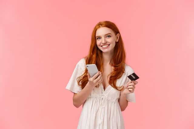 young woman smiling with credit card and smartphone