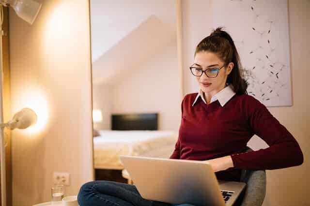 young woman with glasses looking at laptop