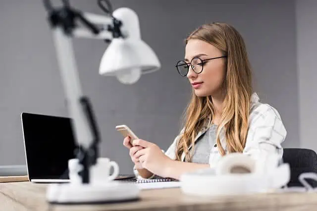 young woman with glasses looking on smartphone