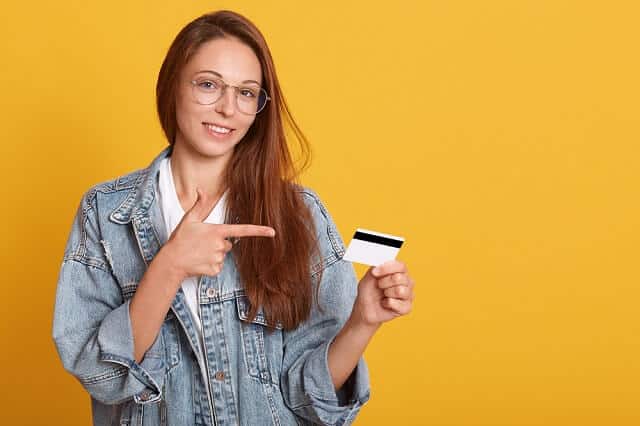 young woman with glasses pointing to credit card